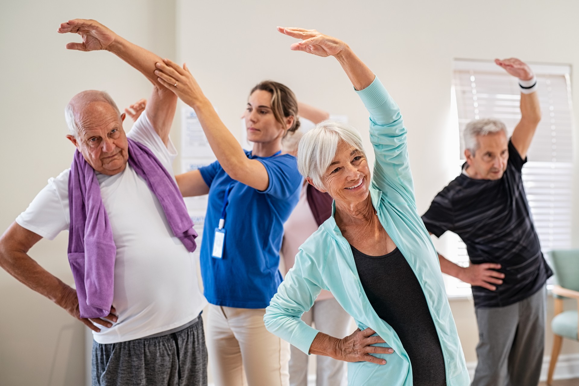 Senior people stretching with trainer at retirement community