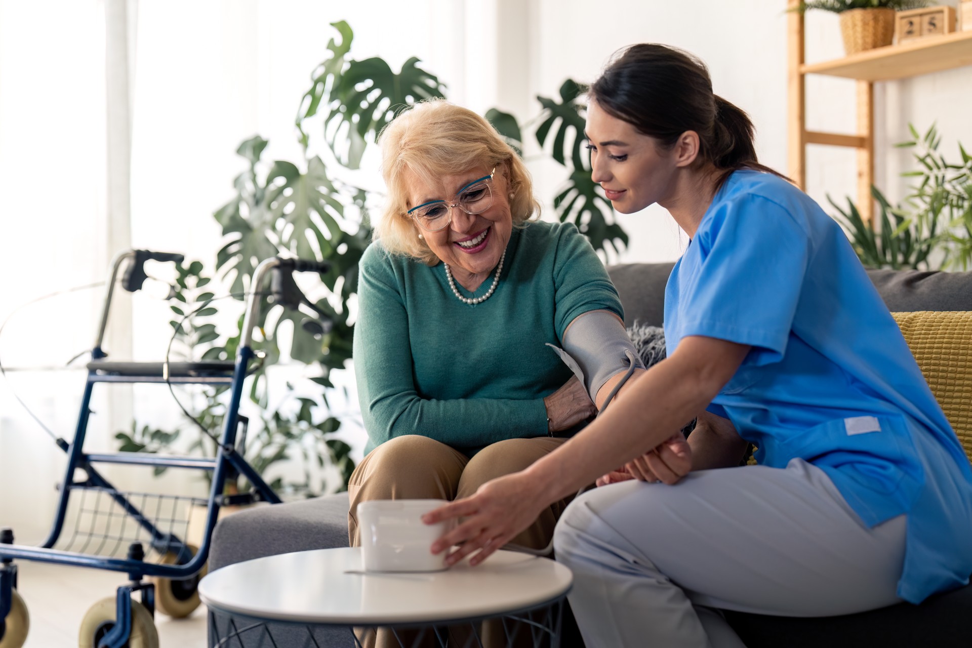 Senior woman and nurse using blood pressure machine